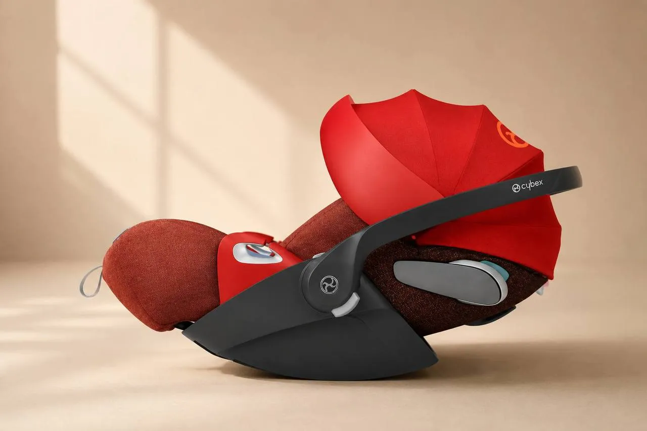 Автолюлька Cybex Cloud красного цвета в горизонтальном положении, снята при дневном свете на бежевом фоне