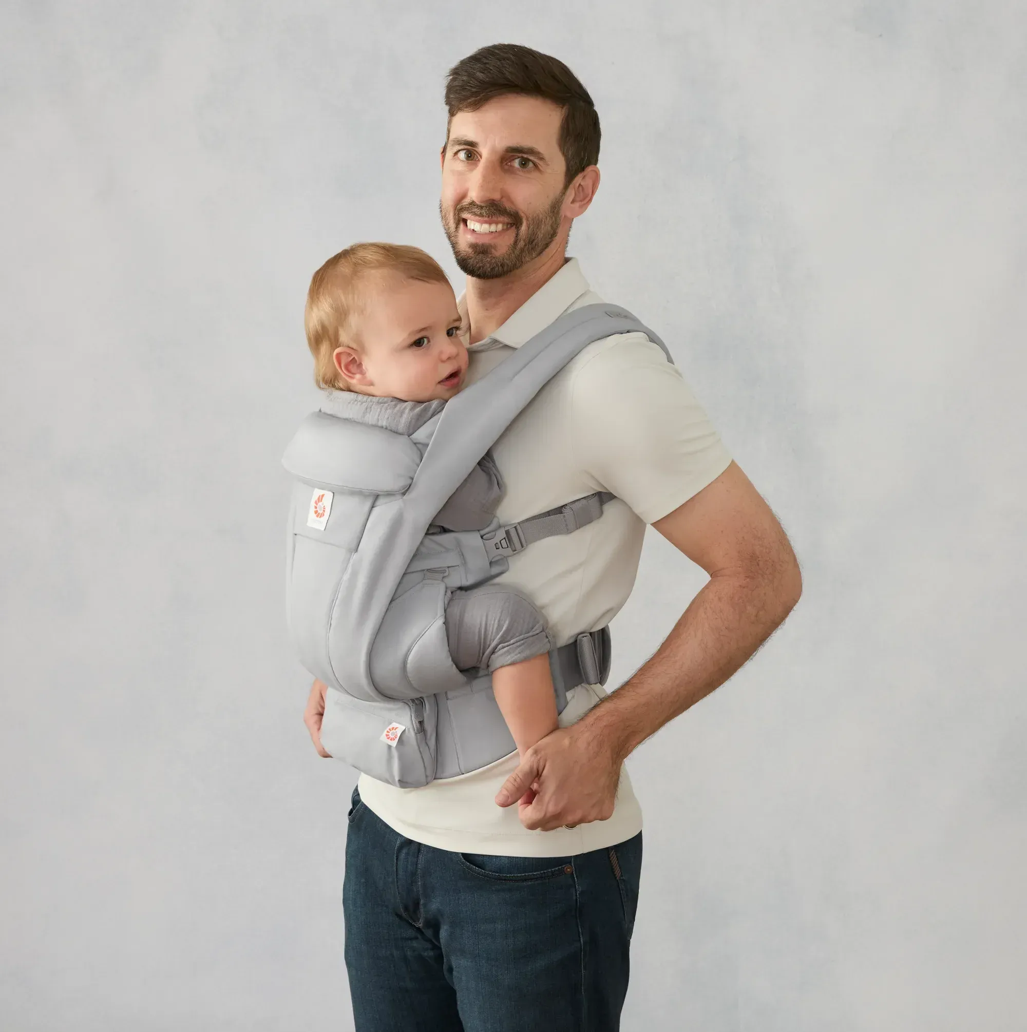 Отец несёт годовалого ребёнка лицом вперёд в переноске Ergobaby Omni Deluxe цвета Pearl Grey